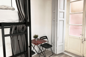 Common area with chairs and table, inside the 12-bed shared room with shared bathroom